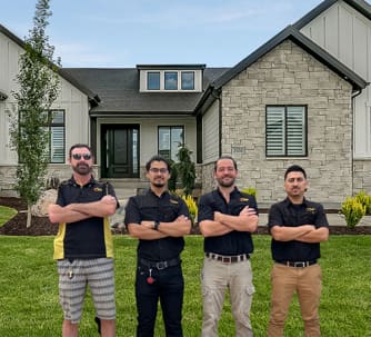 Four plumbers stand proudly in front of a house